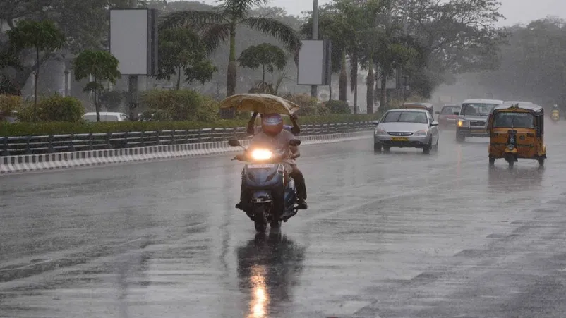 Heavy rain falling in Kerala streets with dark clouds.